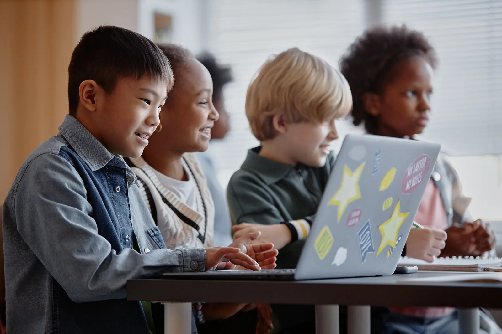 Students using a laptop and books together during a lesson