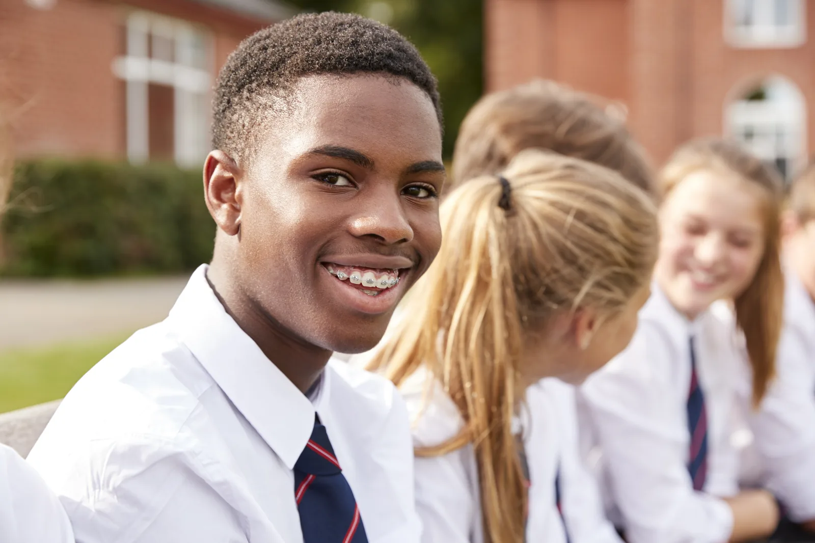 Teenage students in school uniform standing together outside school
