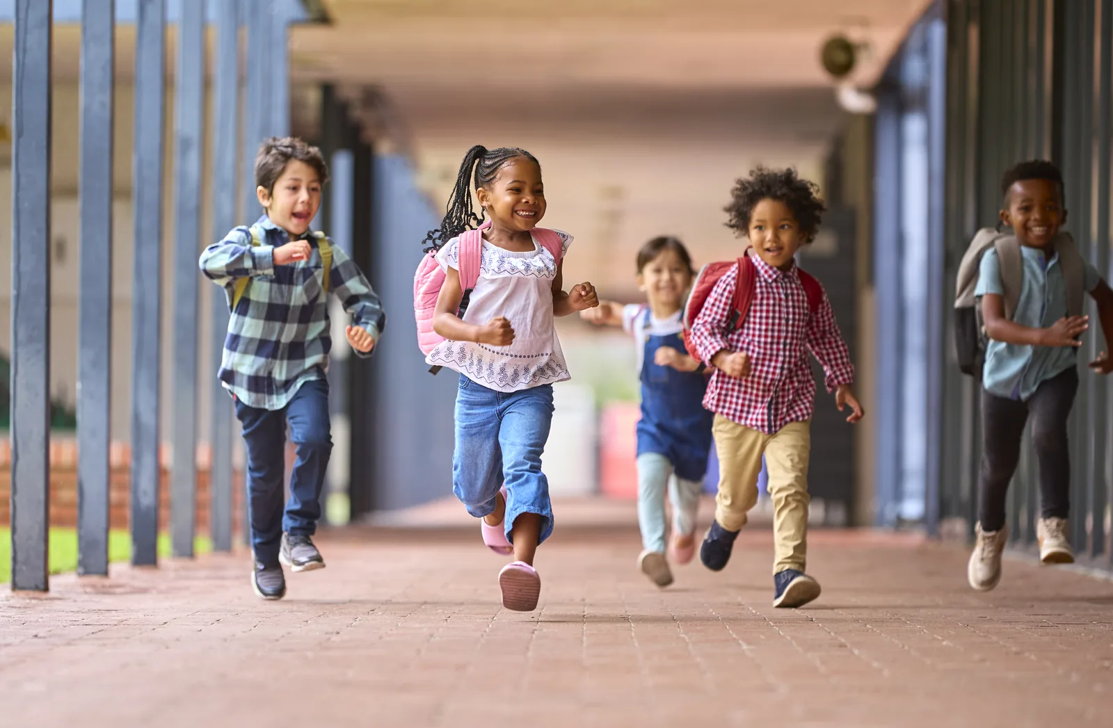 Students running through a school walkway with backpacks