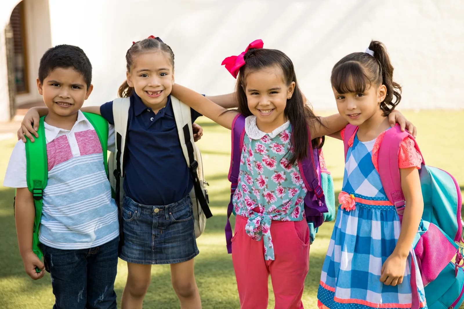 Elementary students with backpacks standing together outside a school