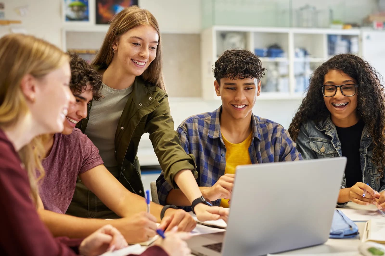 Casually dressed high school students reviewing work together on a laptop