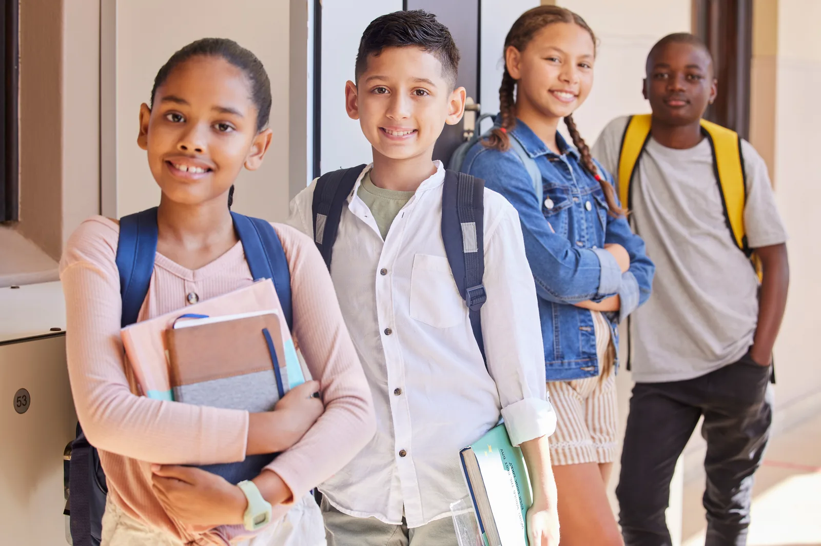 Students carrying books and backpacks in a US school hallway