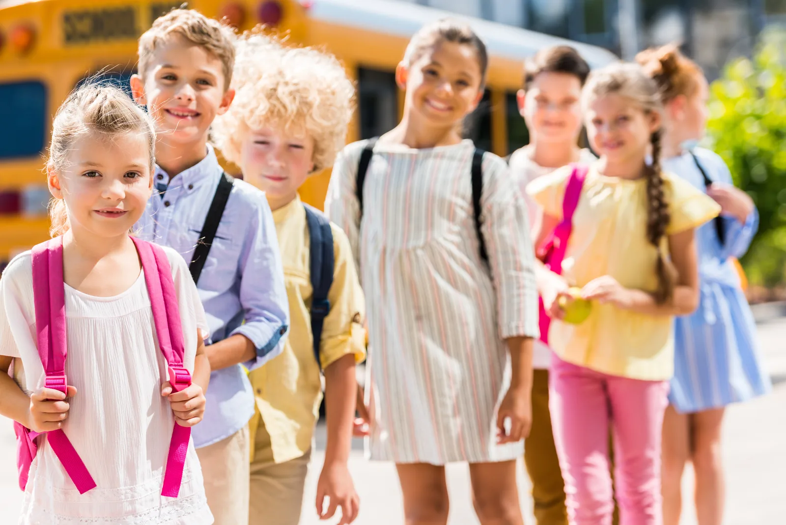 Students standing near a school bus before classes