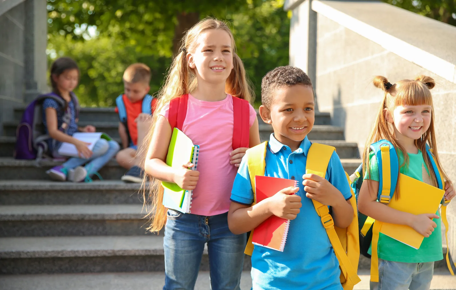 Students outside school carrying notebooks and backpacks