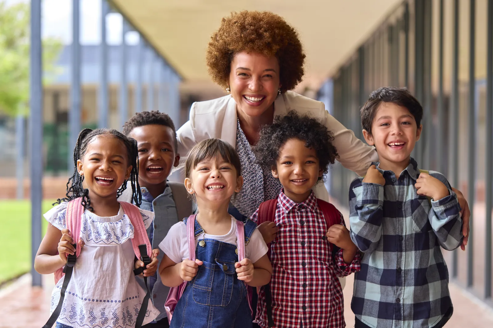 Teacher standing with a diverse group of students in a school hallway