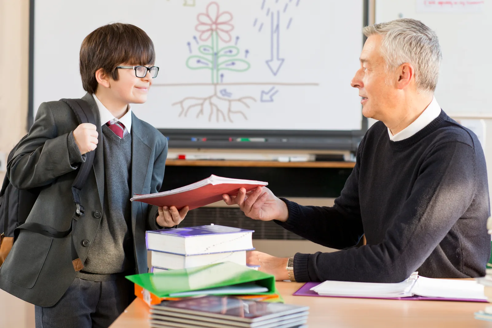 A student receiving application materials from an educator