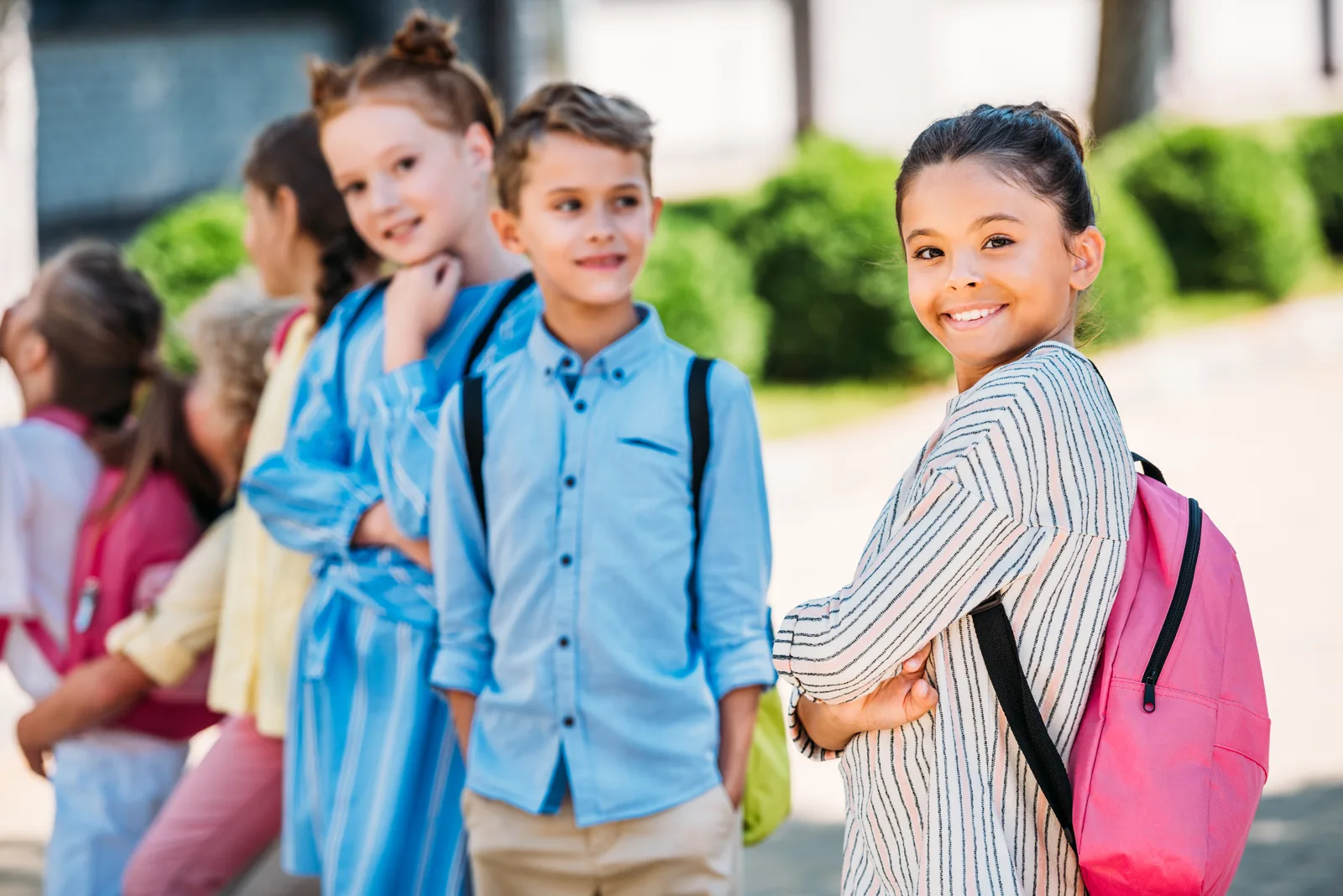 Students with backpacks talking together outside a school