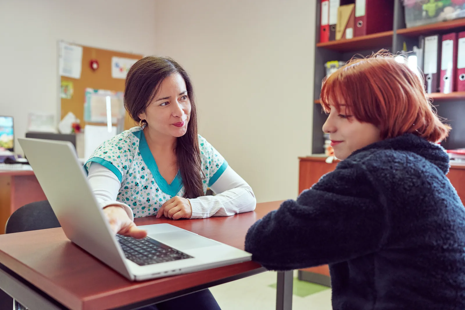 School support professional speaking privately with a teenager at a desk