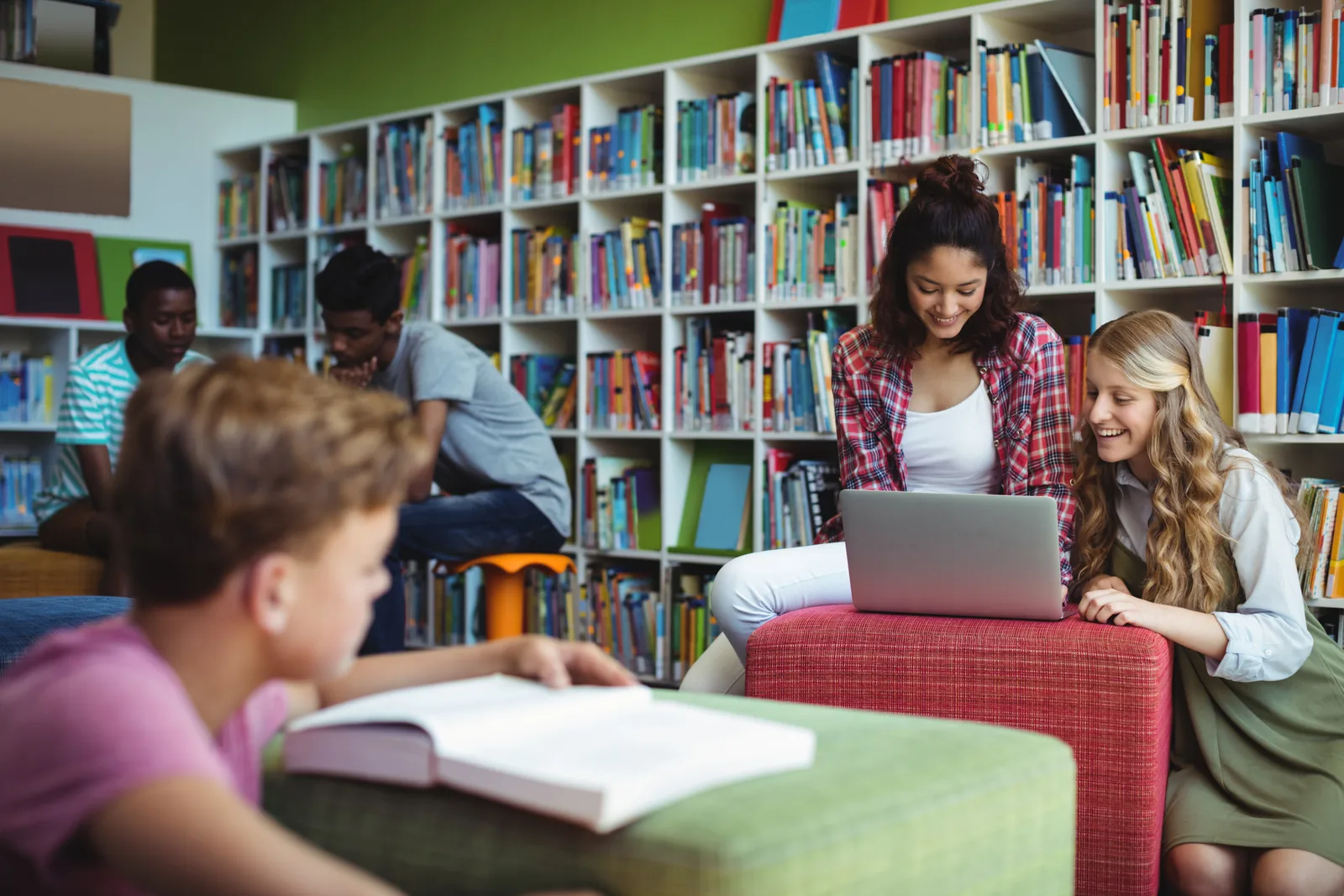 Students reading and working on a laptop together in a library