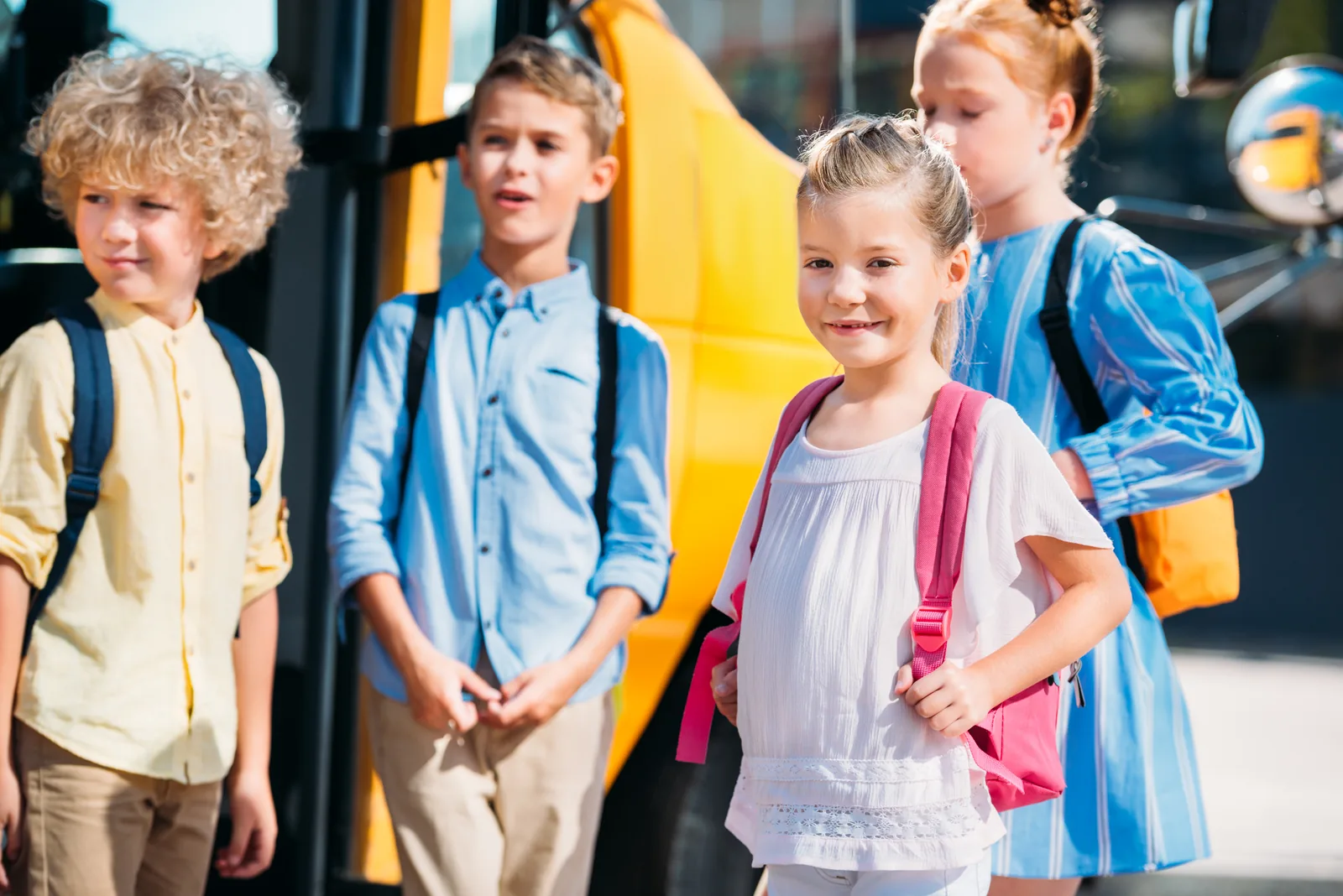 Students standing beside a yellow school bus