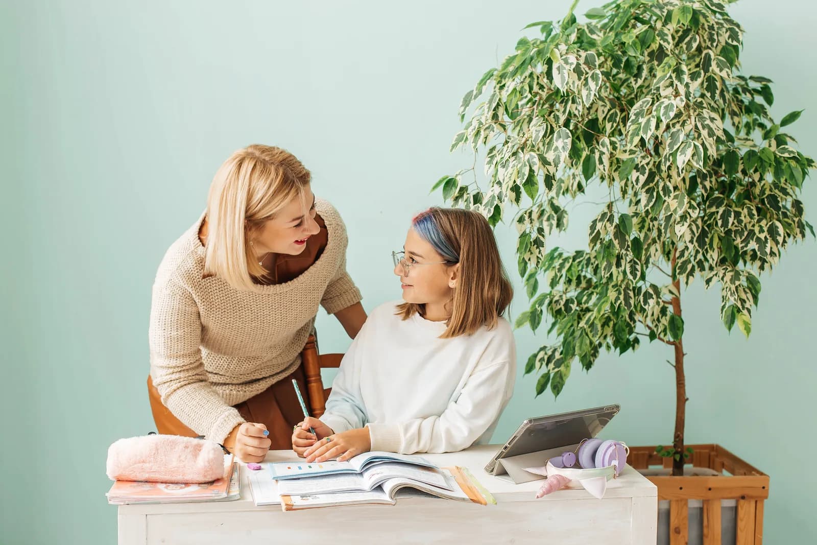 Tutor helping a high school student with written work at a desk