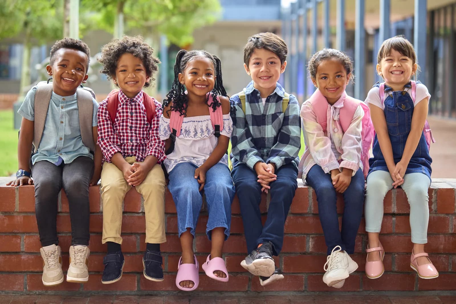 Students sitting together on a low wall outside school